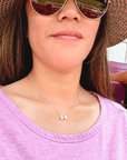 Product lifestyle picture for the Heart and Baseball charm necklace in silver with pink shirt