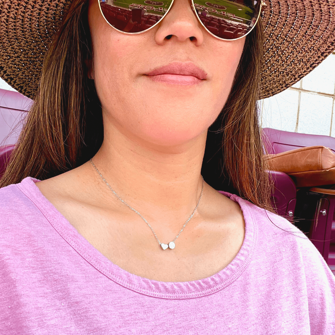 Product lifestyle picture for the Heart and Baseball charm necklace in silver with pink shirt